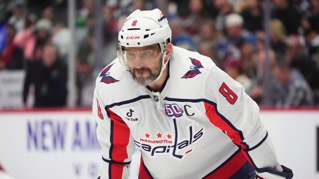 A men's hockey player leans over before a face-off.