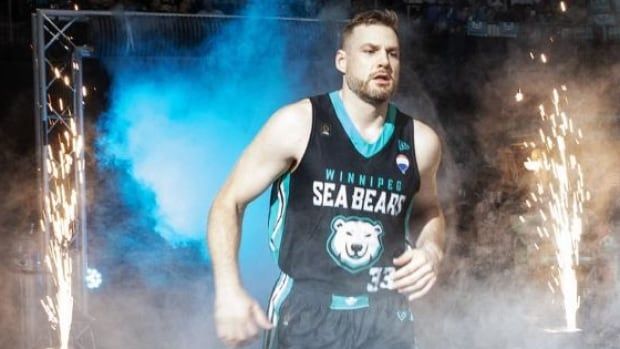 A basketball player comes out of the tunnel with fireworks in the background.