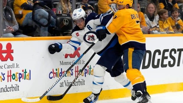 Two players battle for the puck along the boards.