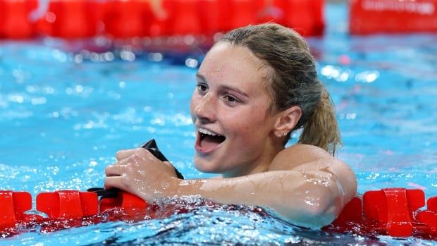 A women's swimmer smiles in the pool.