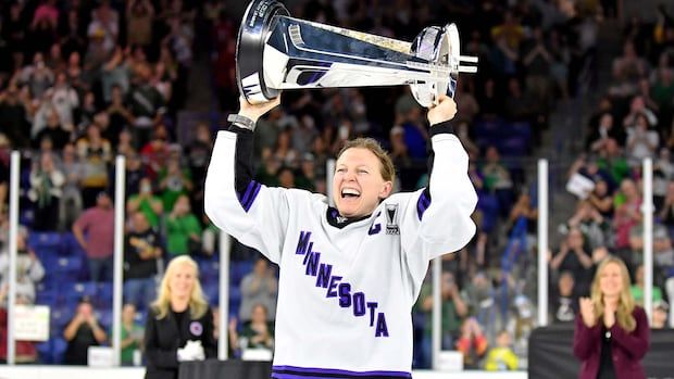 Woman raises trophy over her head.