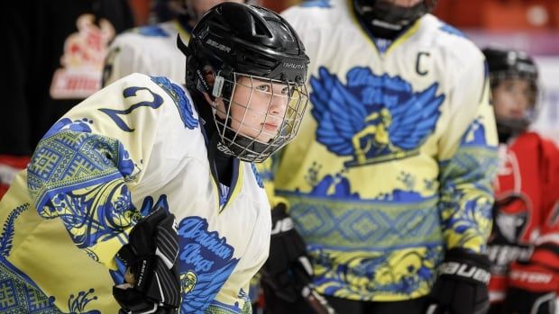 a female hockey player wearing a wire mask helmet in close up