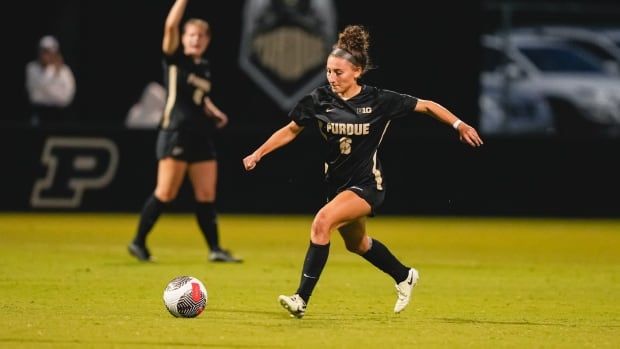 A women's soccer player attempts to kick a ball.