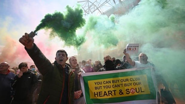 A group of protesters with green smoke outside a soccer stadium. 