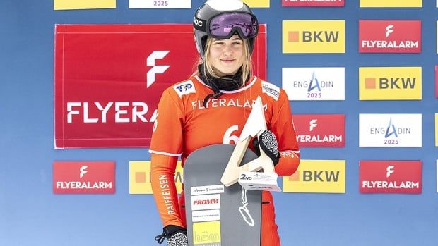 Sophie Hediger of Switzerland stands holding her snowboard after placing second in a women's snowboard cross event on January 26, 2024 in St Moritz, Switzerland. 