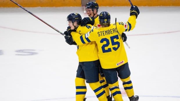 Three hockey players celebrate together.