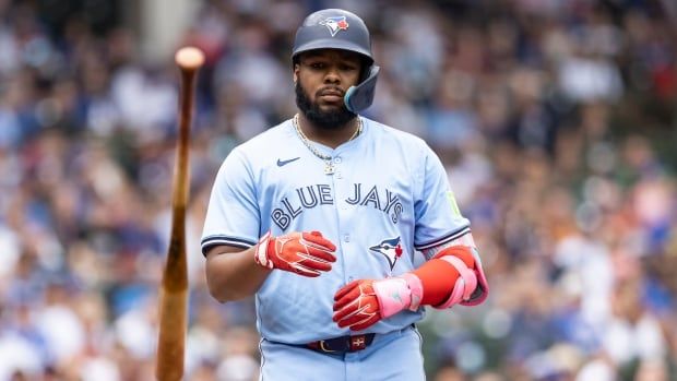 A men's baseball player flips a bat.