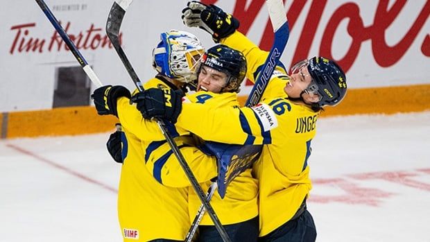 Sweden goaltender Melker Thelin is swarmed by teammates Axel Sandin-Pellikka and Felix Unger Sorum after its 3-2 quarterfinal win over Latvia at the world junior hockey championship in Ottawa on Jan. 2, 2025. 