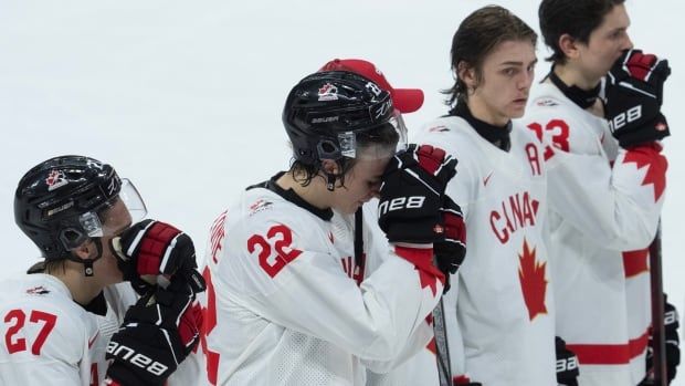 Young Canadian hockey players stand in a row dejected after they are eliminated from the world junior tournament.