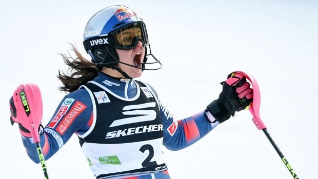 A women's skier raiser her arms in celebration.