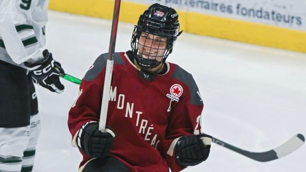 A female hockey player smiling and celebrating after a goal.