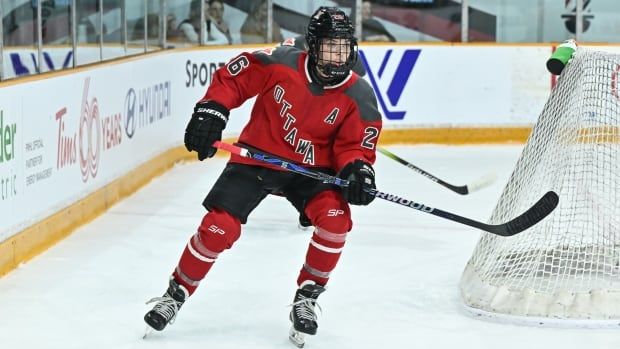 A women's hockey player skates behind the net.