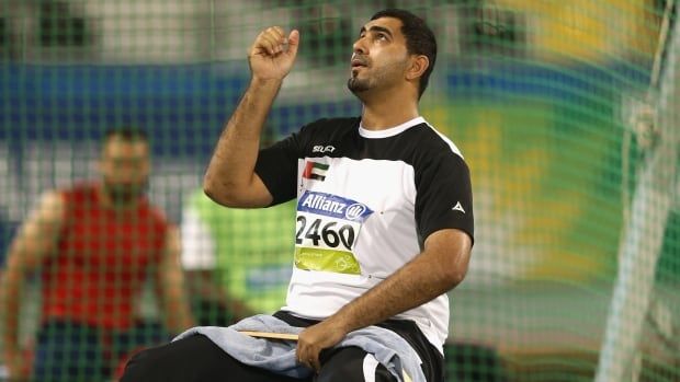 A male Paralympic athlete throws a discus into the air with his right hand.