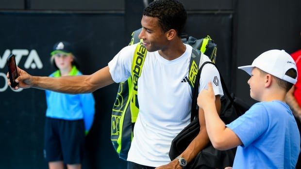 A tennis player takes a selfie with a fan.