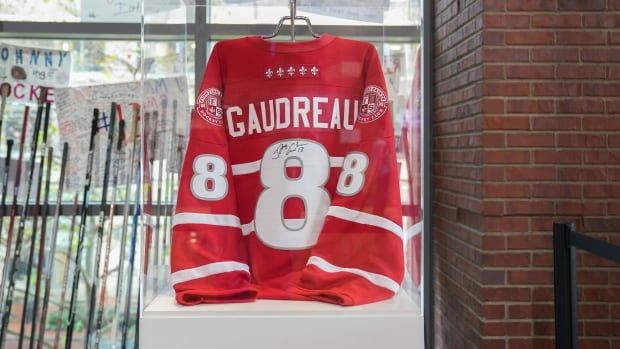 An autographed men's hockey jersey with the number eight hangs in a display case.