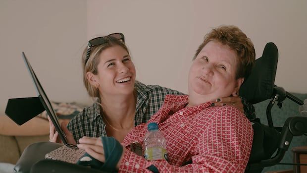 Woman's hockey player smiling with her mom Tammy who is in a wheelchair.