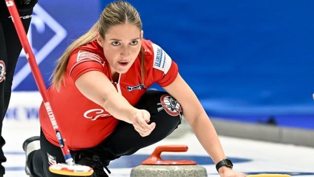 A woman curler throws a stone.