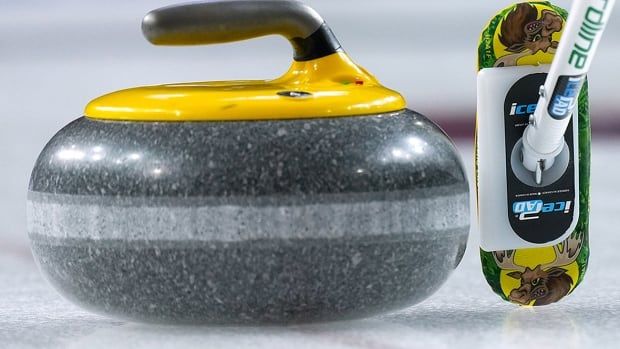 Curling broom and rock pictured beside each other on the ice during 2023 Scotties Tournament of Hearts in Kamloops, B.C.