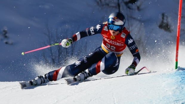 A women's alpine skier carves out a turn.