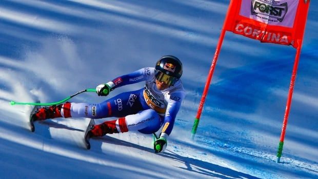 A female alpine skier races past a flag on a downhill course.