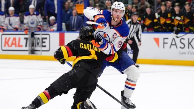 Two male ice hockey players battle for position during a game.