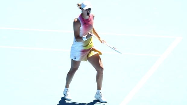 A women's tennis player pumps her fist in celebration.