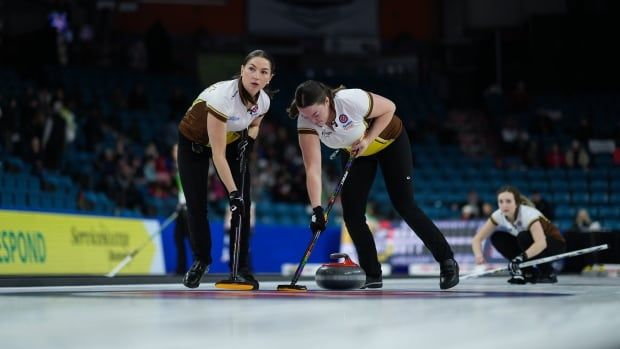 Two female curling player sweeps during a competition.