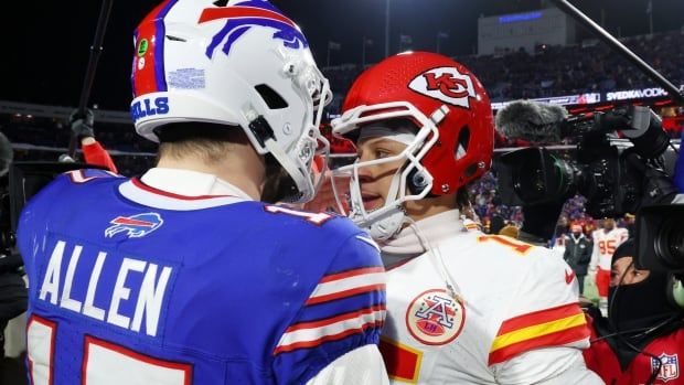 Two men's football quarterbacks greet each other after a game.