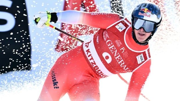 A men's skier is shown while leaning to one side as he stops in the finish area.