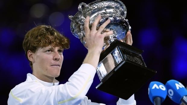 A male tennis player hoists a trophy.