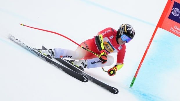 A female alpine skier races past a flag down a suoer-G course.