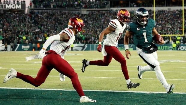 A men's football quarterback runs the ball past defenders.