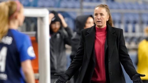 A female soccer coach reacts to players during a game.