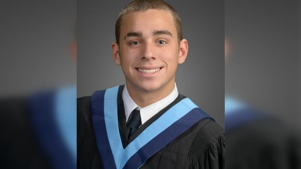 A man smiles in a graduation photo. 