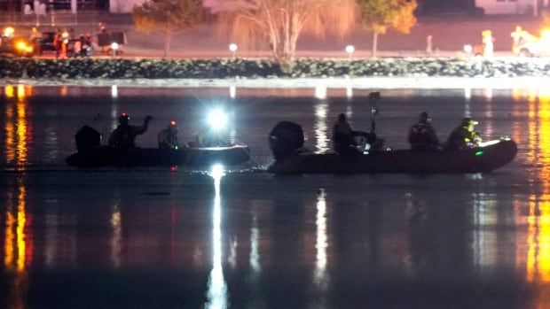 Two boats with flashing lights are seen on a dark night.