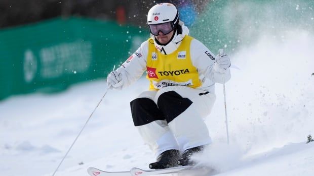 A male freestyle skier skis on a downhill to finish.