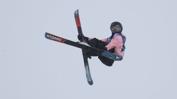 A female freestyle skier soars through the air with her skis crossed.