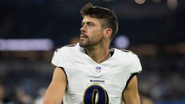 A male football kicker without a helmet looks off to the right on the field.