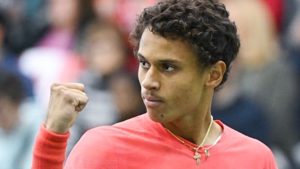 A male tennis player pumps his right fist in celebration.