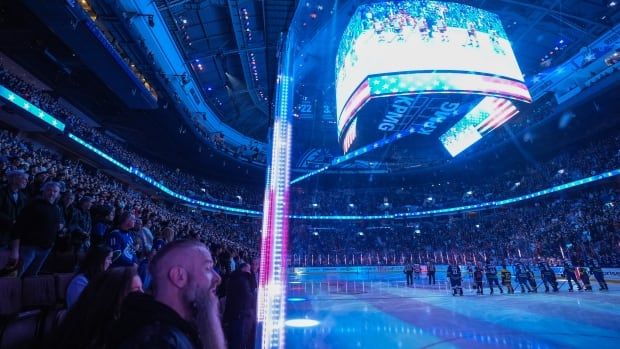 Hockey fans are seen at a game with the U.S. flag projected on the big screen.