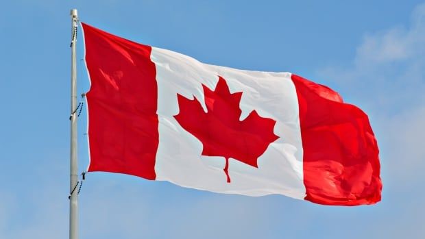 Flag of Canada flying against a blue sky. 