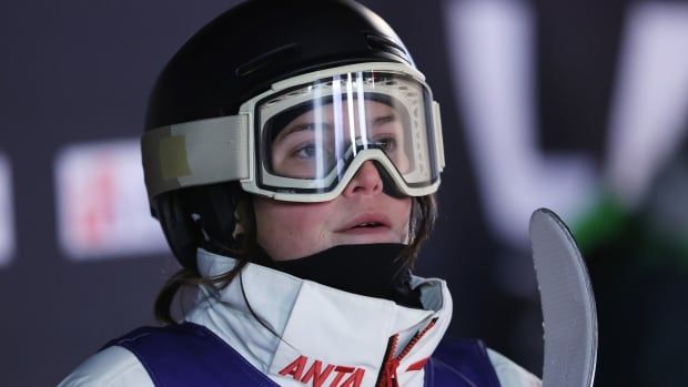 A woman wearing a black helmet and white ski goggles.