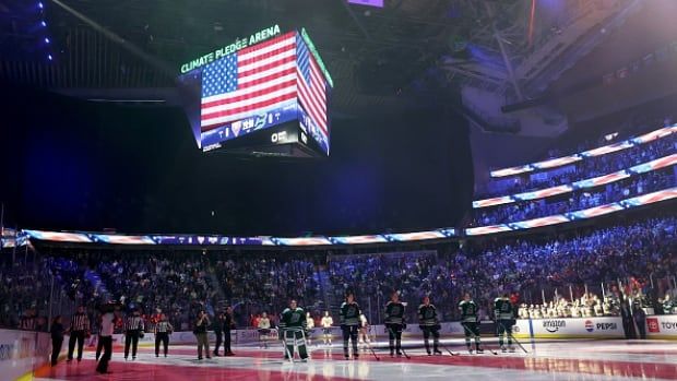 Hockey players stand for national anthem.