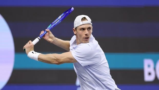 A men's tennis player hits a shot.