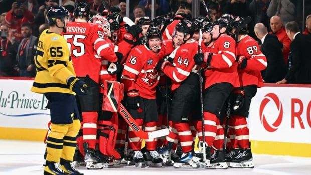 A team celebrates on ice in a group after a game-winning goal.