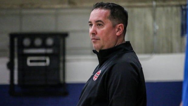 A male futsal coach in black team Canada sweater watches on during practice.