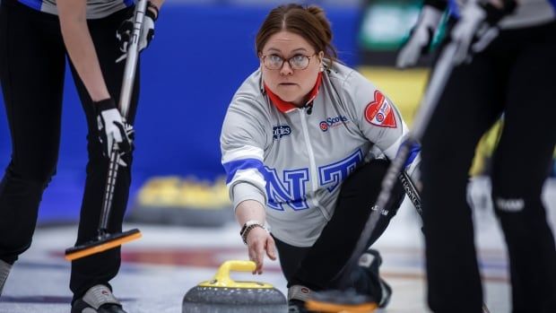 A female curling skip makes a shot.