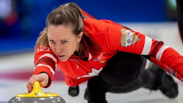 A female curling skip delivers a rock.