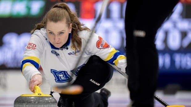 A female curling skip throws a rock.