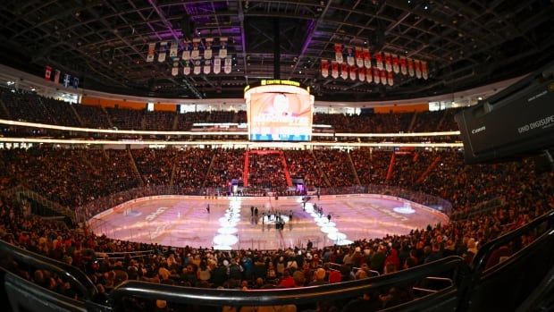 A hockey arena glowing in red is shown from a wide angle.